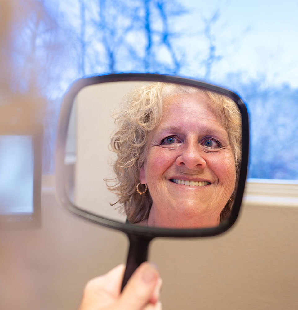 headshot of patient smiling brightly within the mirror