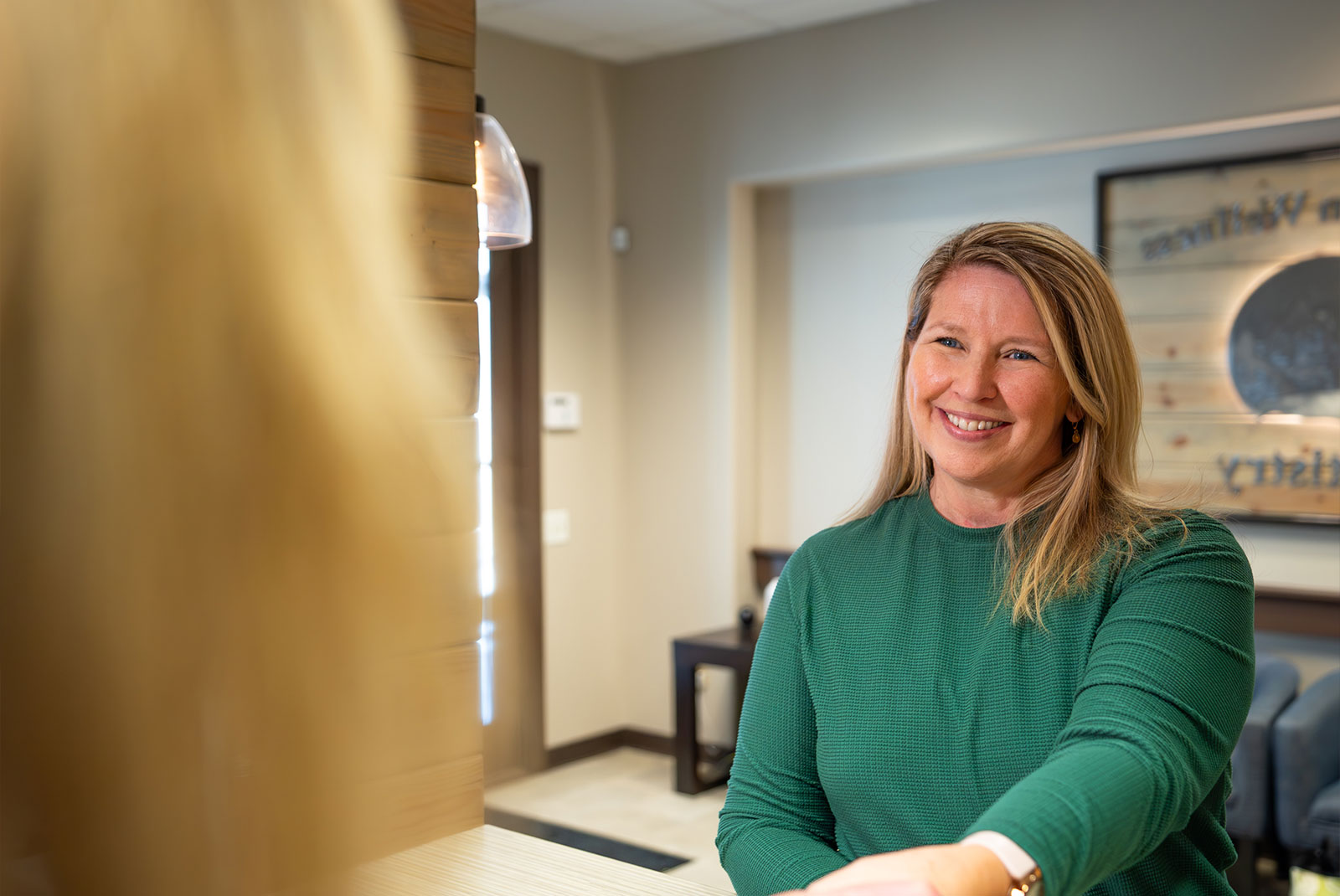 headshot of patient smiling brightly while being helped at the front desk