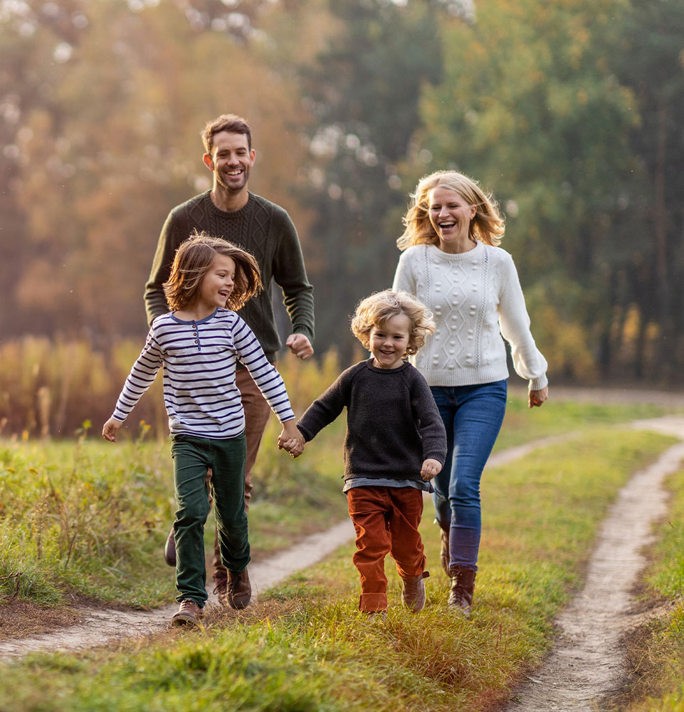 family smiling and walking through a trail