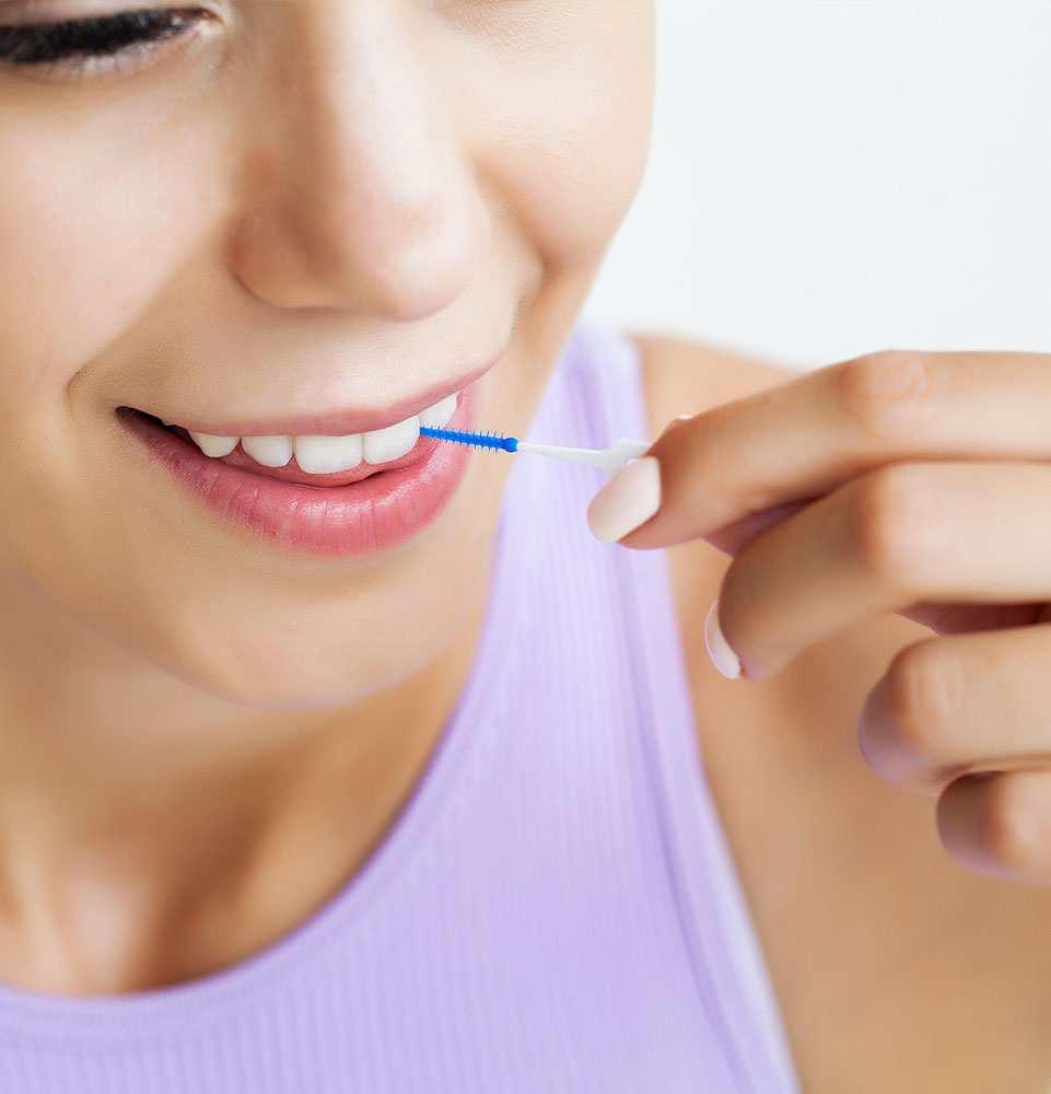 The woman uses brushes to clean the interdental spaces