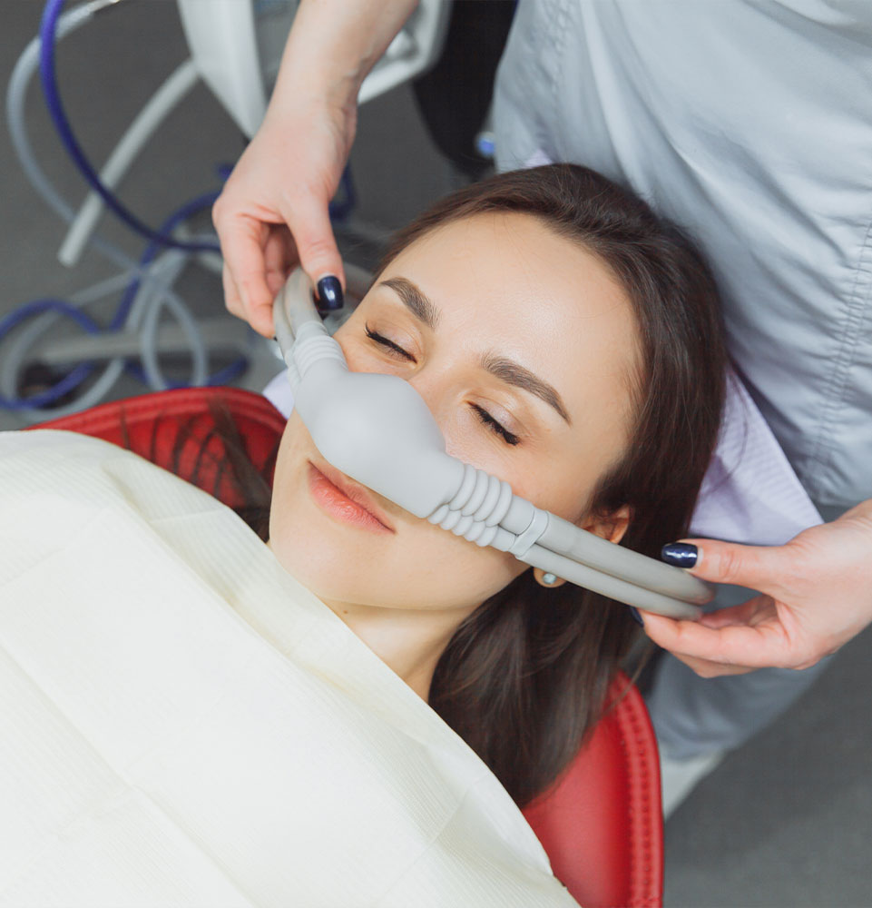 dentist puts inhalation sedative mask on his patient.