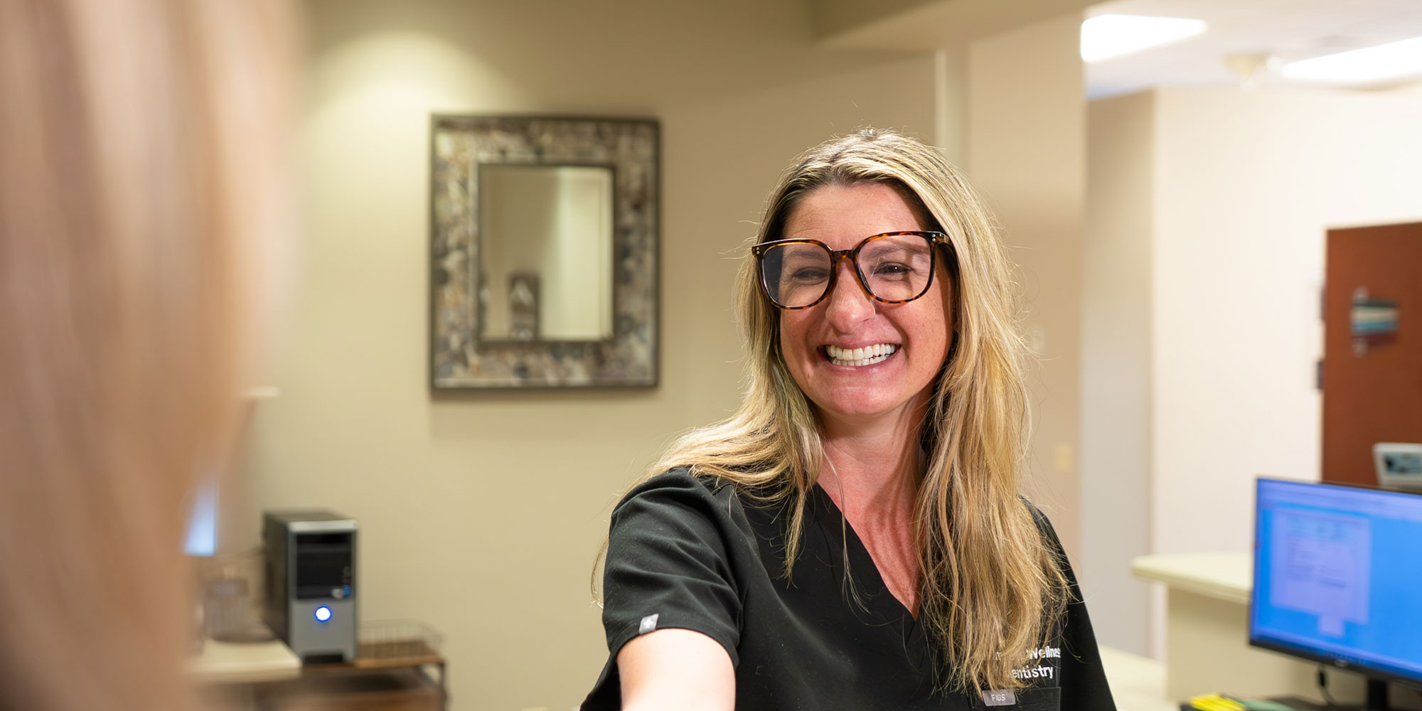 staff member helping patient at the front desk of the dental practice