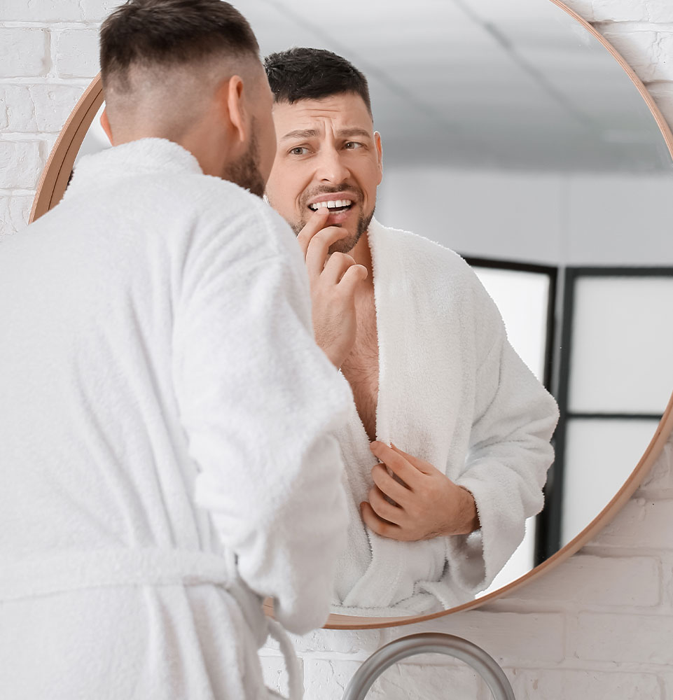 mature male checking mouth in bathroom mirror after dealing with some mouth pain