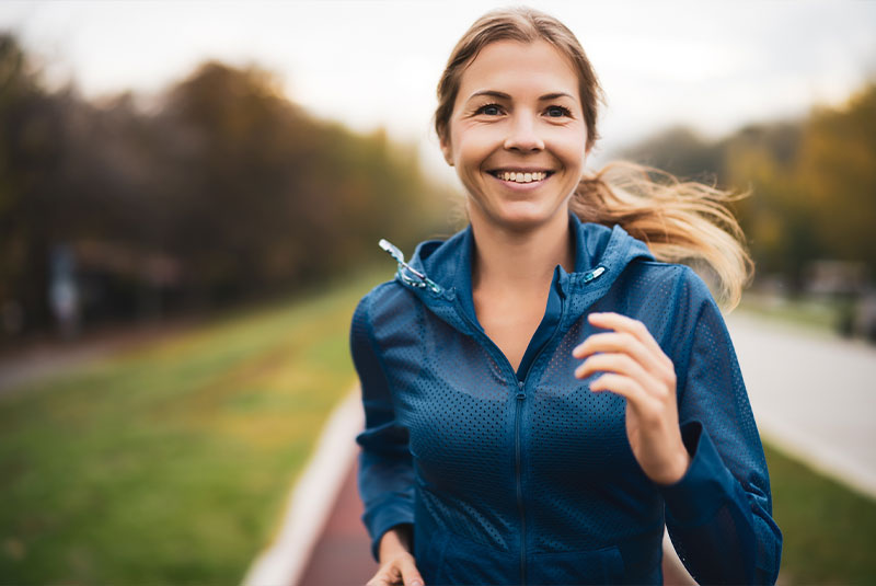 Beautiful adult woman is jogging outdoor on cloudy day in autumn.
